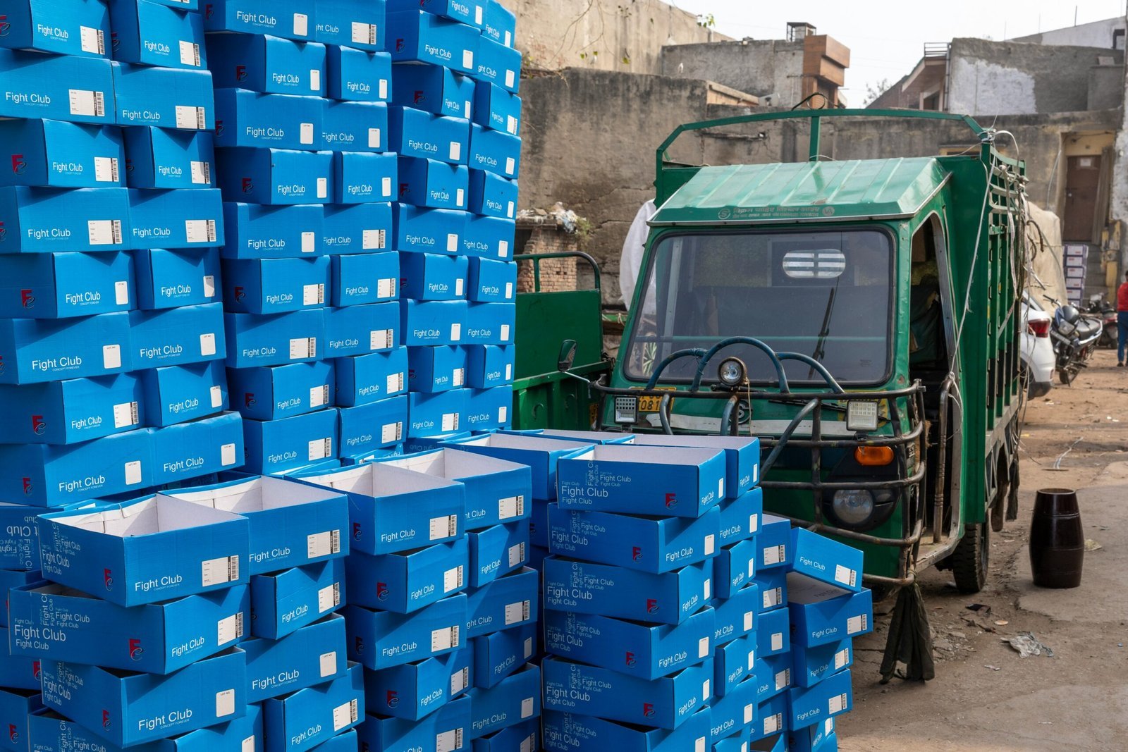 a green truck parked next to a pile of blue boxes